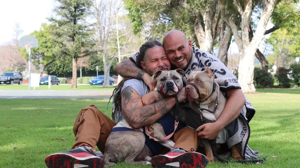 Willy and Chris of Earthship Journey sitting outdoors with their dogs